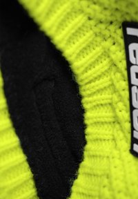 Knitted yellow fabric with a ribbed texture, revealing a black fleece interior. Includes a tag with 'PRO' branding.