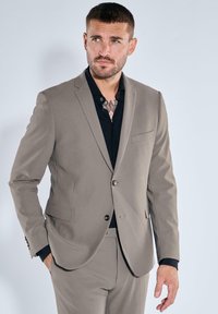 Light gray suit with a tailored fit, featuring a single button closure, notch lapels, and a chest pocket, paired with a black dress shirt.