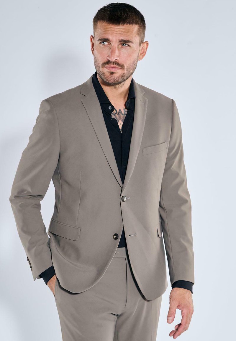 Light gray suit with a tailored fit, featuring a single button closure, notch lapels, and a chest pocket, paired with a black dress shirt.