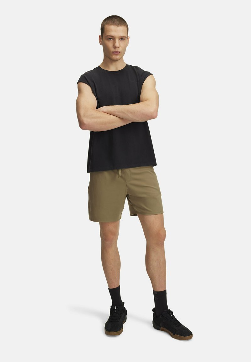 Čierny bezrukávový tričko, khaki šortky a čierne tenisky. Model stojí so skríženými rukami, čo ukazuje neformálny atletický štýl.