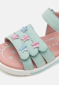 Sandali sintetici blu chiaro con tre cinturini decorati con stelle in glitter rosa e blu, una soletta rosa con motivi floreali e una suola bianca.
