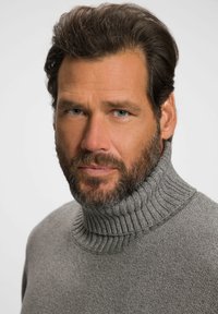 Grijs gebreid trui met een hoge ribbelkraag. De stof lijkt zacht en textuur te hebben, aangevuld met een subtiel patroon.