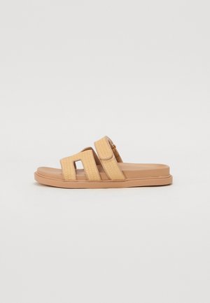 Sandales à talon ouvert avec une semelle en caoutchouc beige et des sangles jaunes texturées présentant un motif croisé. Deux fermetures velcro ajustables.