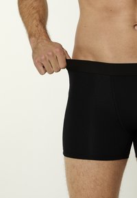 Boxer briefs neri con una morbida cintura elastica, realizzati in un tessuto liscio ed elastico. Lo stile presenta un design aderente.