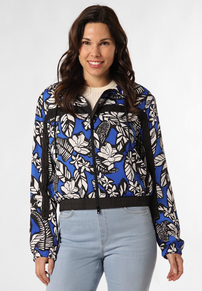 Gekürzte Jacke mit einem blauen Hintergrund und weißen sowie schwarzen Blumenmustern, elastischem Bund, Reißverschluss und langen Ärmeln.