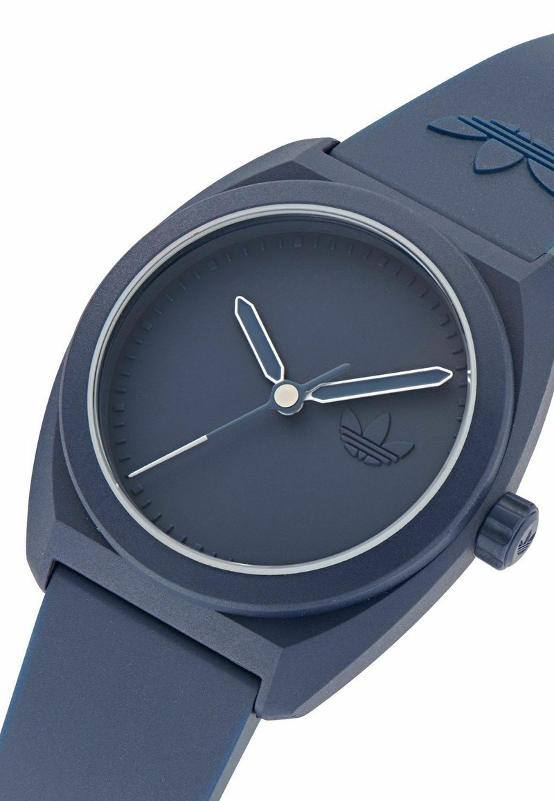 Orologio in silicone blu navy con quadrante rotondo, design minimalista e lancette delle ore e dei minuti argentate. Caratterizzato da un cinturino testurizzato e logo del marchio.