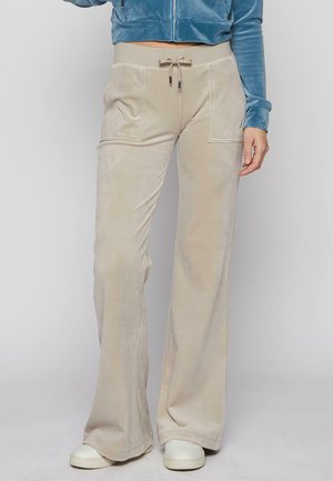 Beige Kick-Flare-Hosen aus weichem Material mit zwei Fronttaschen, einem verstellbaren Kordelzugbund und glatter Textur.