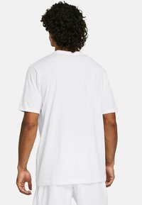 T-shirt en coton blanc avec un col rond classique, des manches courtes et un ourlet droit, affiché de dos. Aucun motif supplémentaire.
