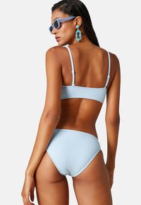 Jasnoniebieski bikini z prążkowanym wzorem, z regulowanymi ramiączkami i wysokim stanem, podkreślający teksturowany materiał oraz dopasowany krój.