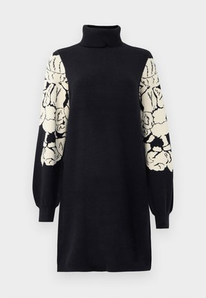 Svart strikket turtleneck kjole med lange ballongsleeves som har hvite og svarte abstrakte blomstermønstre.