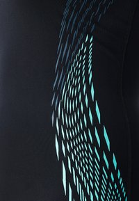 Tissu athlétique noir avec un motif de formes géométriques turquoise, présentant une texture lisse et des détails de couture contrastants.