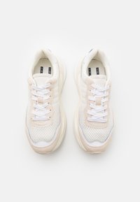 Sneakers med en meshinstrument i beige och vitt, med en texturerad mockadetalj, platta vita snören och en vadderad sula.