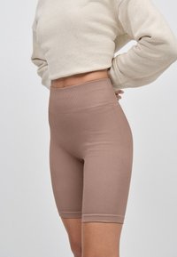 Bruna ribbade shorts med hög midja, tillverkade av stretchigt tyg, med en sömlös design och en slät textur.