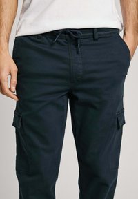Navy cargobroeken met een trekkoord in de taille, zijzakken en een gladde textuur, ontworpen voor comfort en functionaliteit in casual omgevingen.
