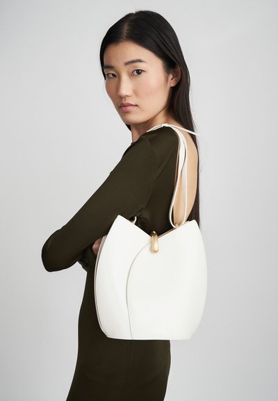 Borsa a mano in pelle crema con design a pieghe, accessori in oro e cinture sottili. Texture liscia, forma moderna e stile minimalista.