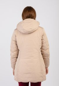 Beige geïsoleerde jas met een capuchon, met een getailleerde taille, lange mouwen en een gladde, gestructureerde stof. De zoom valt onder de taille.
