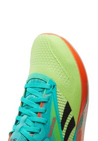 Sapatilha atlética em malha verde com atacadores aqua, detalhes laranja e logotipo preto. Parte superior texturizada e sola transparente para respirabilidade e suporte.