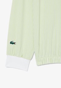Vêtement léger rayé vert et blanc avec poignets élastiques. Dispose d'un petit logo crocodile brodé sur la manche gauche.