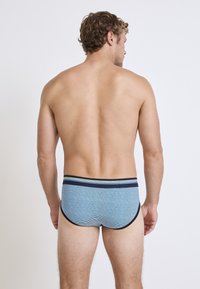 Herrboxershorts i ljusblått, med ett tunt randigt mönster och midjeband i marinblått med gröna detaljer. Mjuk tyg och åtsittande design.