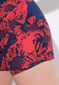 Blommönstrade shorts med stora röda blommor mot en mörkblå bakgrund. Tillverkade av ett mjukt, stretchy tyg. Har rena sömmar.