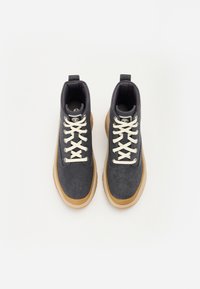 Mørk denim høy-topp joggesko med beige snørebånd, gummisåler og en buet design. Har en trekkstrop på tungen.