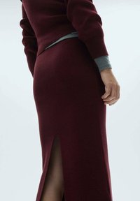 Gonna a coste bordeaux con spacchi laterali, design aderente, vita elastica e fodera grigia a contrasto in vita.