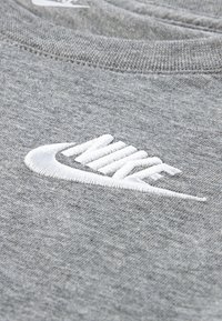 Sweat-shirt gris à texture douce avec un logo Nike blanc brodé sur le devant. Le col est rond et côtelé.