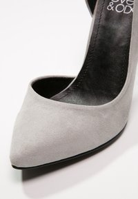 Décolleté grigio in suede con punta appuntita, texture liscia e interno nero. Senza hardware o dettagli visibili.