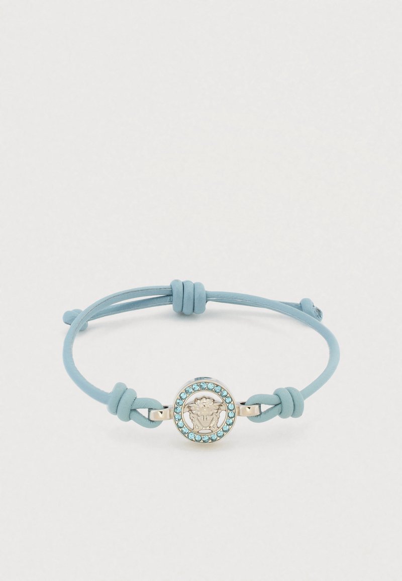 Bracelet en cuir bleu avec un médaillon central en argent orné d'une tête de lion, entouré de strass bleu clair.