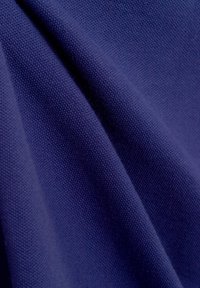 Katoen stof in een diep marineblauw met een gestructureerde weving, die zachte kreukels en een uniform patroon laat zien.