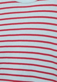 Fehér szövet közelről, egyenletesen elhelyezkedő vízszintes piros csíkokkal.