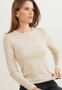 Beige Langarmshirt aus einem weichen, strukturierten Stoff. Mit Rundhalsausschnitt und dezentem, hellen Muster. Schmal geschnittenes Design.