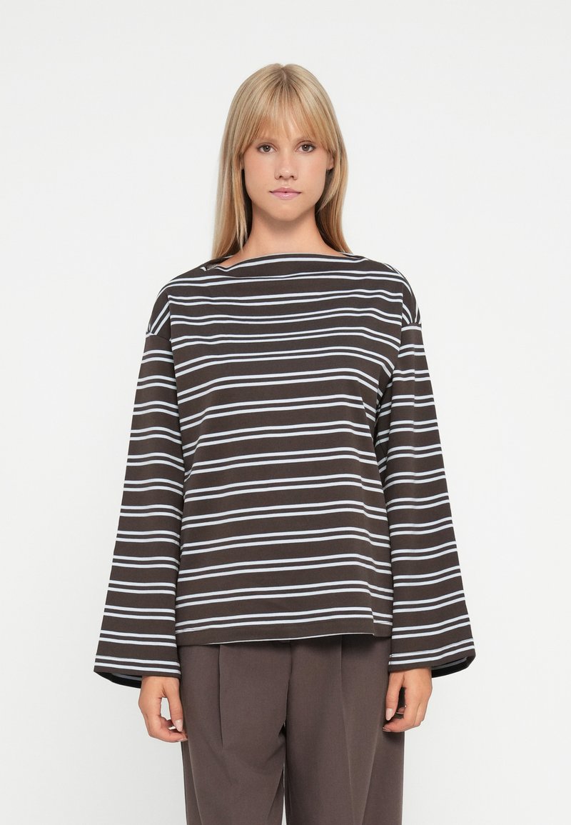 Top a maniche lunghe a righe marroni con linee azzurre, featuring un collo a barca e una vestibilità rilassata. Abbinato a pantaloni scuri a vita alta.