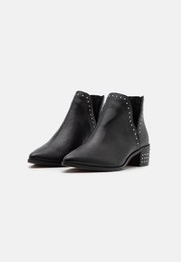 Bottes noires en cuir montantes avec un bout pointu, des accents cloutés sur le côté et un talon carré avec des détails cloutés.
