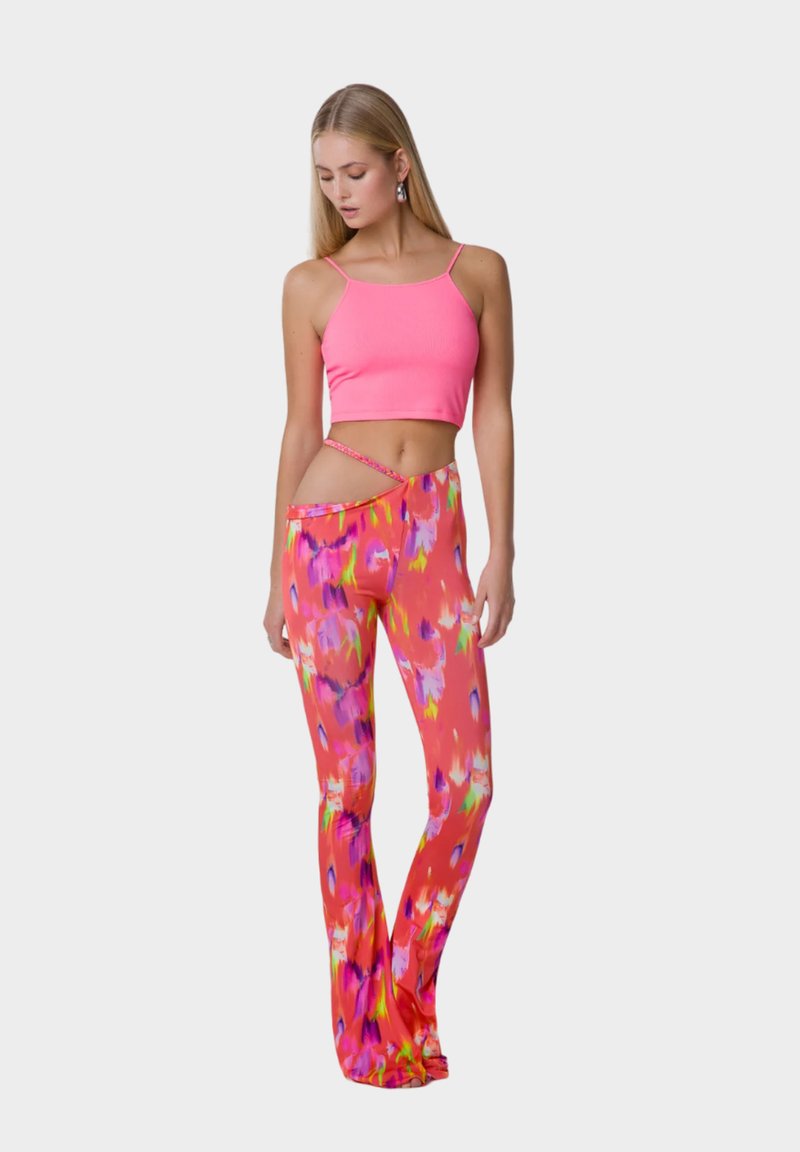 Top corto a coste rosa abbinato a pantaloni a campana con stampa floreale dai colori vivaci di rosa, viola e verde.