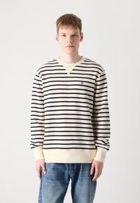 Stripet langermet sweatshirt i off-white og marineblå. Har v-hals og strukturert stoff, med ribbestrikkede mansjetter og nederkant. Lite logo på brystet.
