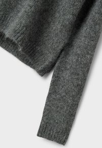 Manche de pull en tricot peluche gris foncé avec bord-côte sur fond clair.