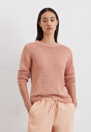 Gebreide trui in zacht roze, met een ronde halslijn en geribbelde manchetten. Gecombineerd met licht perzikkleurige broek met koordjes. Eenvoudige textuur.