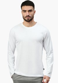 Langärmliges weißes T-Shirt aus leichtem Stoff, mit rundem Ausschnitt und figurbetontem Schnitt. Keine sichtbaren Muster oder Grafiken.