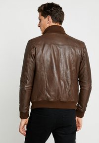 Pruun nahkjope ribadega krae ja varrukatega. Omab sujuvat tekstuuri ja kontrastset õmblust, loodud kehakujundust silmas pidades.