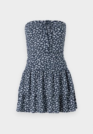 Floral strapless dress in navy with white flowers. Features smocked bodice and tiered ruffled skirt. Made of lightweight fabric.