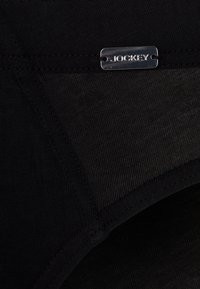 Intimo nero caratterizzato da una texture liscia, un'etichetta con il logo Jockey e un design senza cuciture in vita e nelle aperture delle gambe.