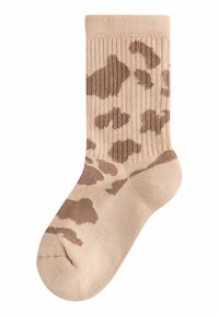 Calzino beige a metà polpaccio con motivi di stampa leopardata irregolare marroni e texture a coste su uno sfondo bianco.