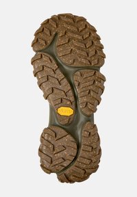 Profil einer braunen Vibram-Sohle mit robusten Mustern, versehen mit einem Logo und der Größe 38, eingeprägt auf einem grünen Untergrund, entworfen für den Einsatz im Freien.