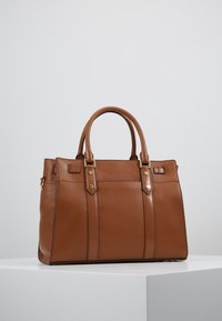 Braune Lederhandtasche mit strukturierter Oberfläche, zwei Griffen, goldenen Hardware-Akzenten und einer strukturierten Form mit vertikalen Nähten.