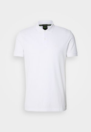 Witte polo shirt gemaakt van katoen met korte mouwen, een knoopsluiting met twee knopen en een geborduurd logo op de linkerborst. Glad textuur.