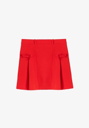 Czerwona plisowana spódnica wykonana z miękkiego materiału, z dwiema kokardkami po bokach oraz dopasowanym pasem, który nadaje zarysowanej sylwetce.