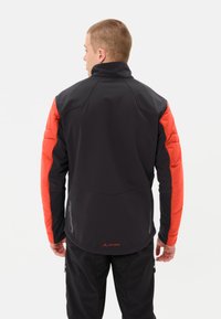 Veste noire et orange avec un col montant, des sections d'épaules matelassées et une texture lisse. Affiche un logo dans le bas du dos.