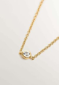Collar de cadena de oro que presenta un colgante de piedra clara redonda, con un acabado liso y enlaces entrelazados. Diseño simple y elegante.