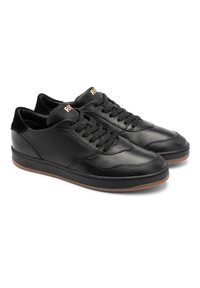 Baskets en cuir noir à tige basse, surface texturée, bout rond, lacets noirs, accents dorés et semelle en caoutchouc.